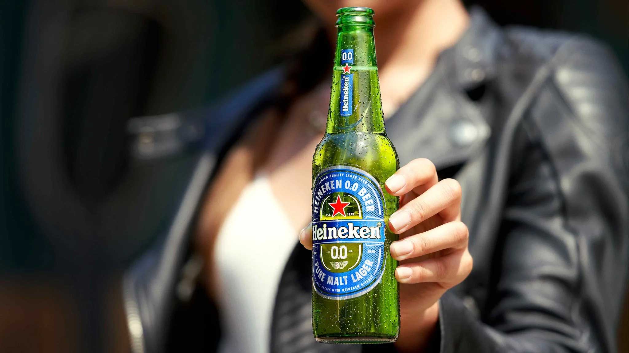 Mulher segurando garrafa Heineken 0.0